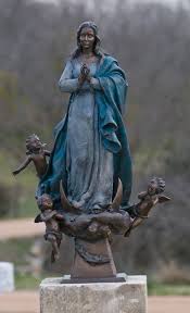 Bronze statue of Our Lady of the Rosary in prayer, attended by cherubs, on the cemetery grounds