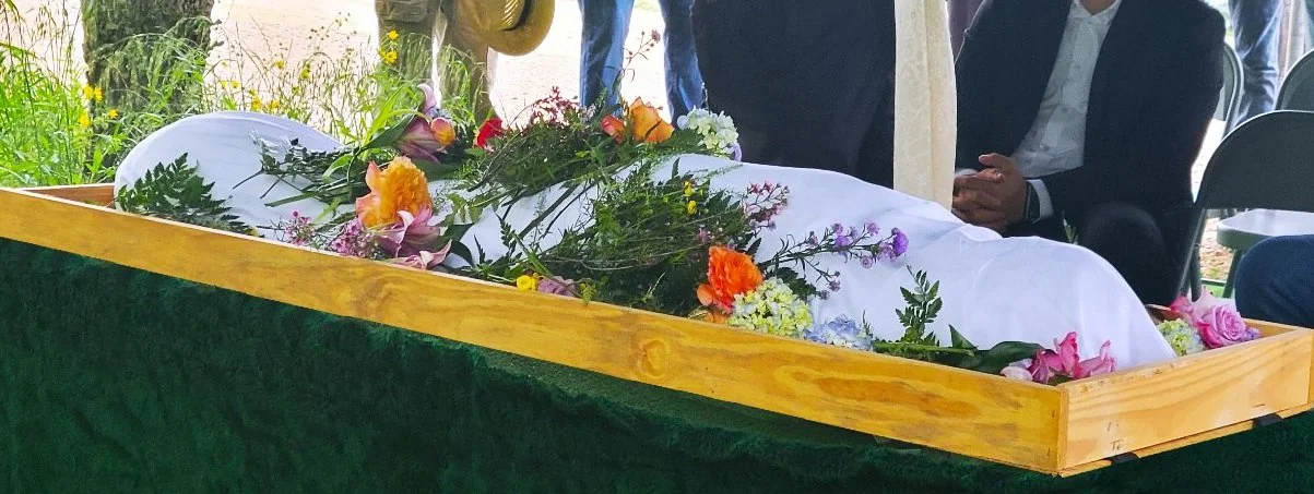 A natural burial in a simple wood casket adorned with flowers